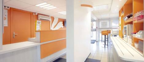 Un moderno vestíbulo de hotel con un mostrador de recepción, zona de estar y un mostrador con servicios.