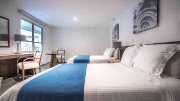 Una habitación de hotel con dos camas, un escritorio, una silla, una lámpara y una ventana.