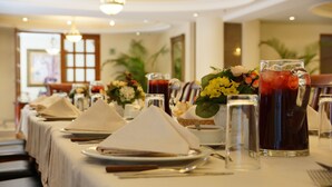 A dining table set with white napkins, plates, cutlery, and pitchers of iced drinks, with a floral centerpiece. - Suites Obelisk (Mexico City)