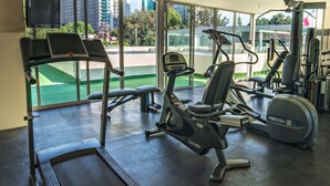 A gym with cardio machines, weight equipment, and large windows offering city views. - Suites Obelisk (Mexico City)