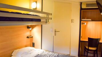 Una habitación de hotel compacta con literas, un escritorio y una silla.