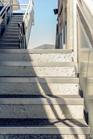 A set of concrete steps leading up to a building with a metal railing on the right.