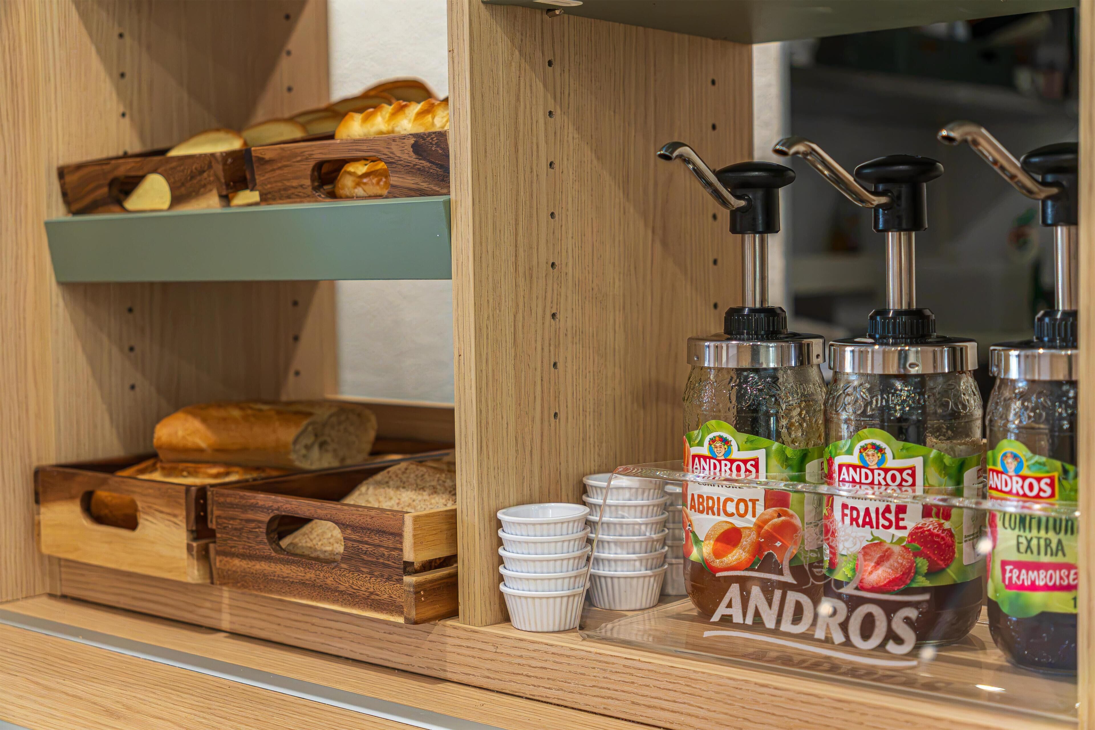 Mostrador de panadería con pan y pastelería, y condimentos de la marca Andros.