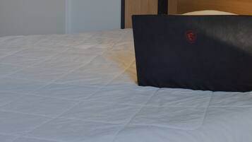 Una laptop sobre una cama con una colcha blanca.