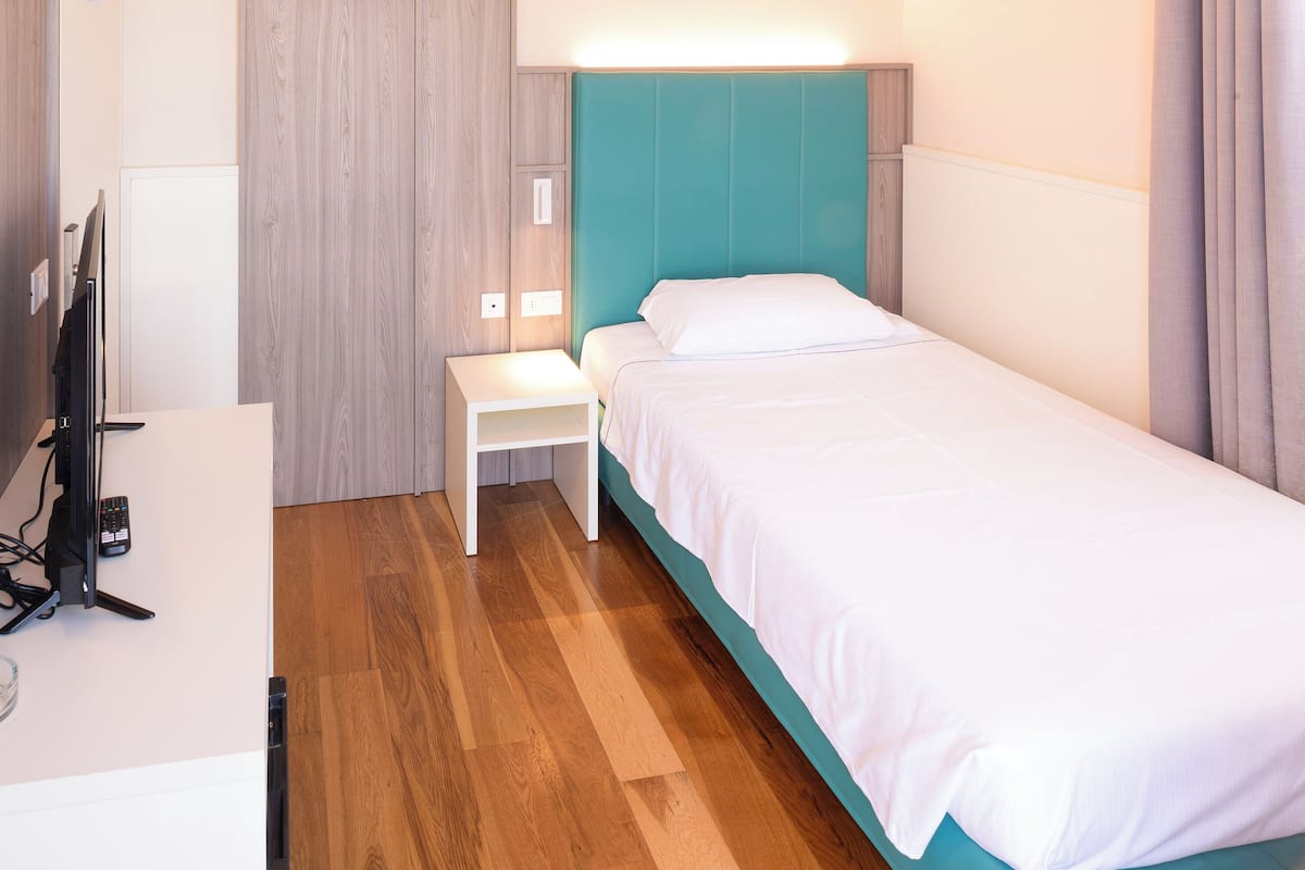 A hotel room with a bed, a desk, and a television.