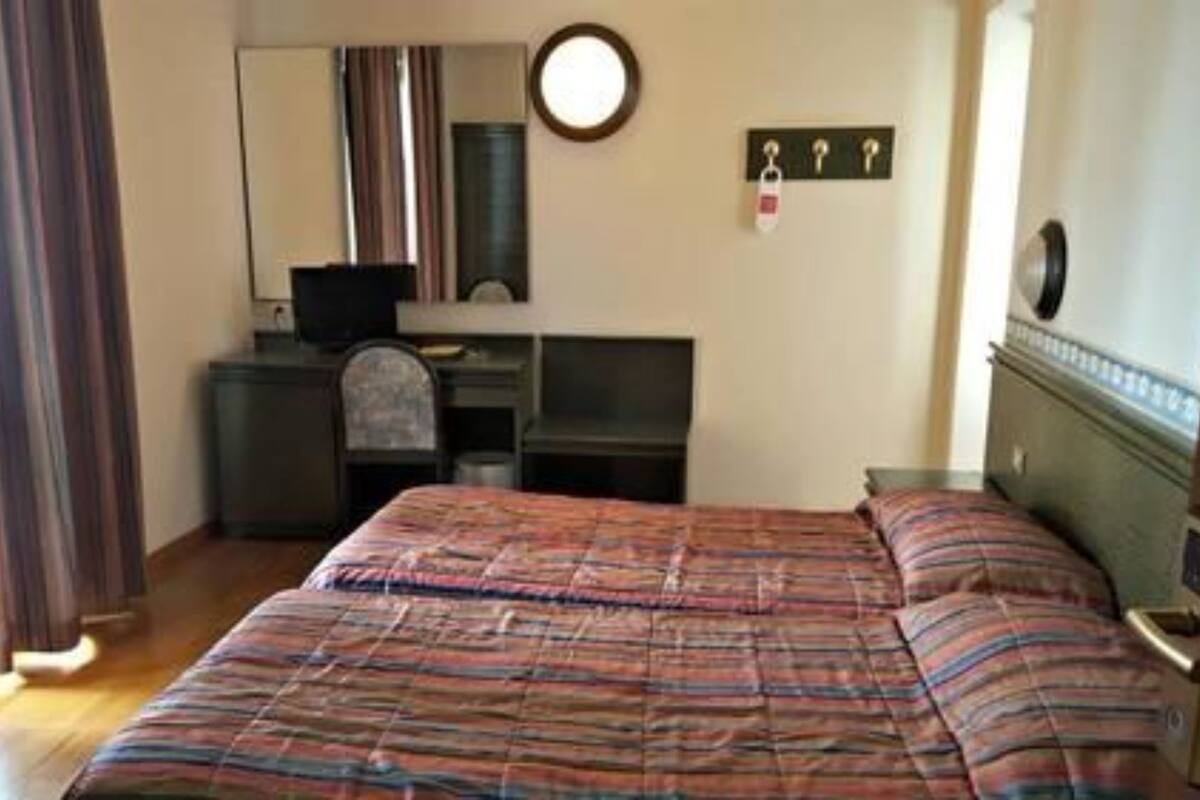 A bedroom with a bed, a desk, a chair, a television, and a mirror.