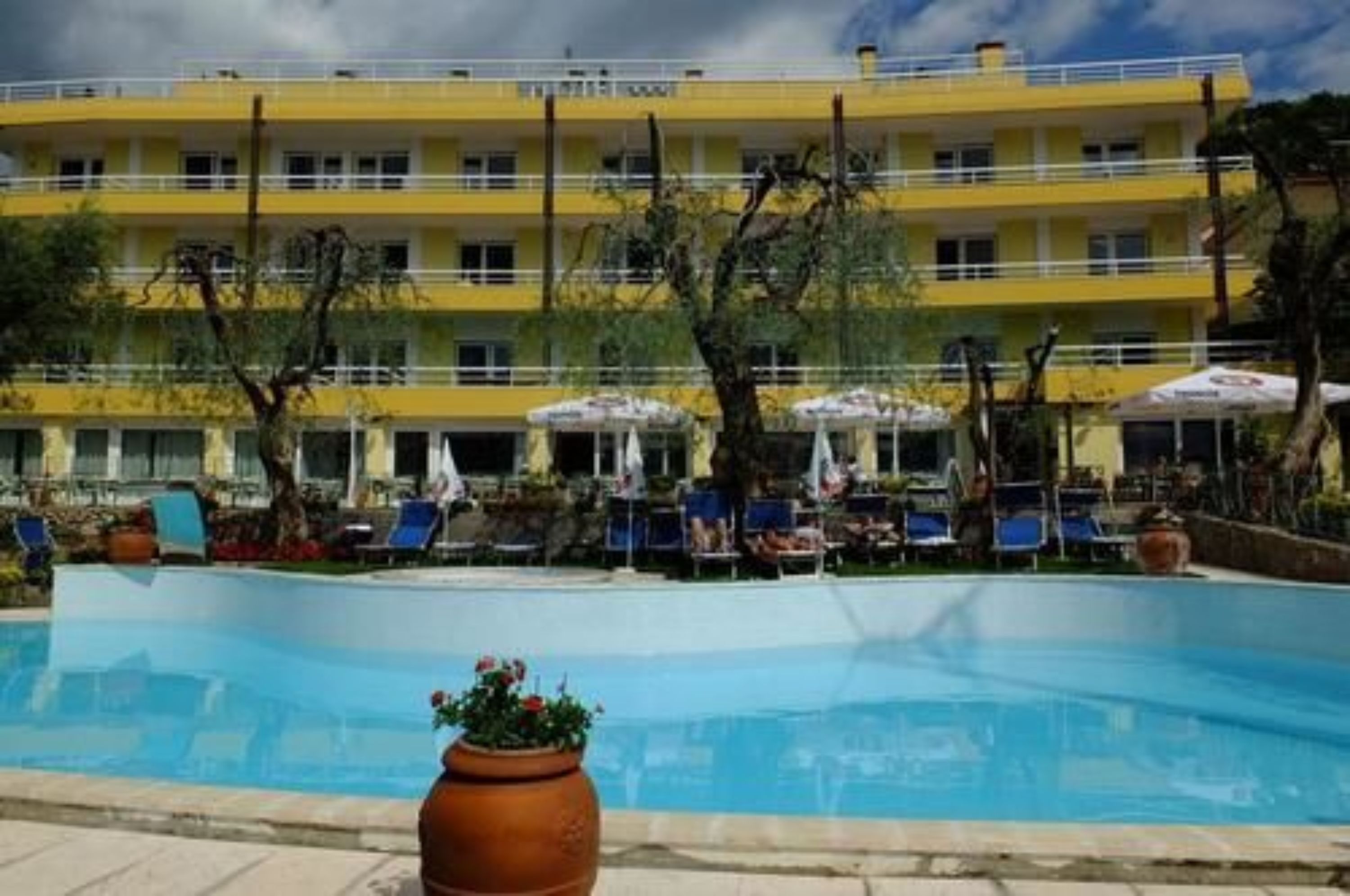 A hotel with a pool, outdoor seating, and a yellow building facade.