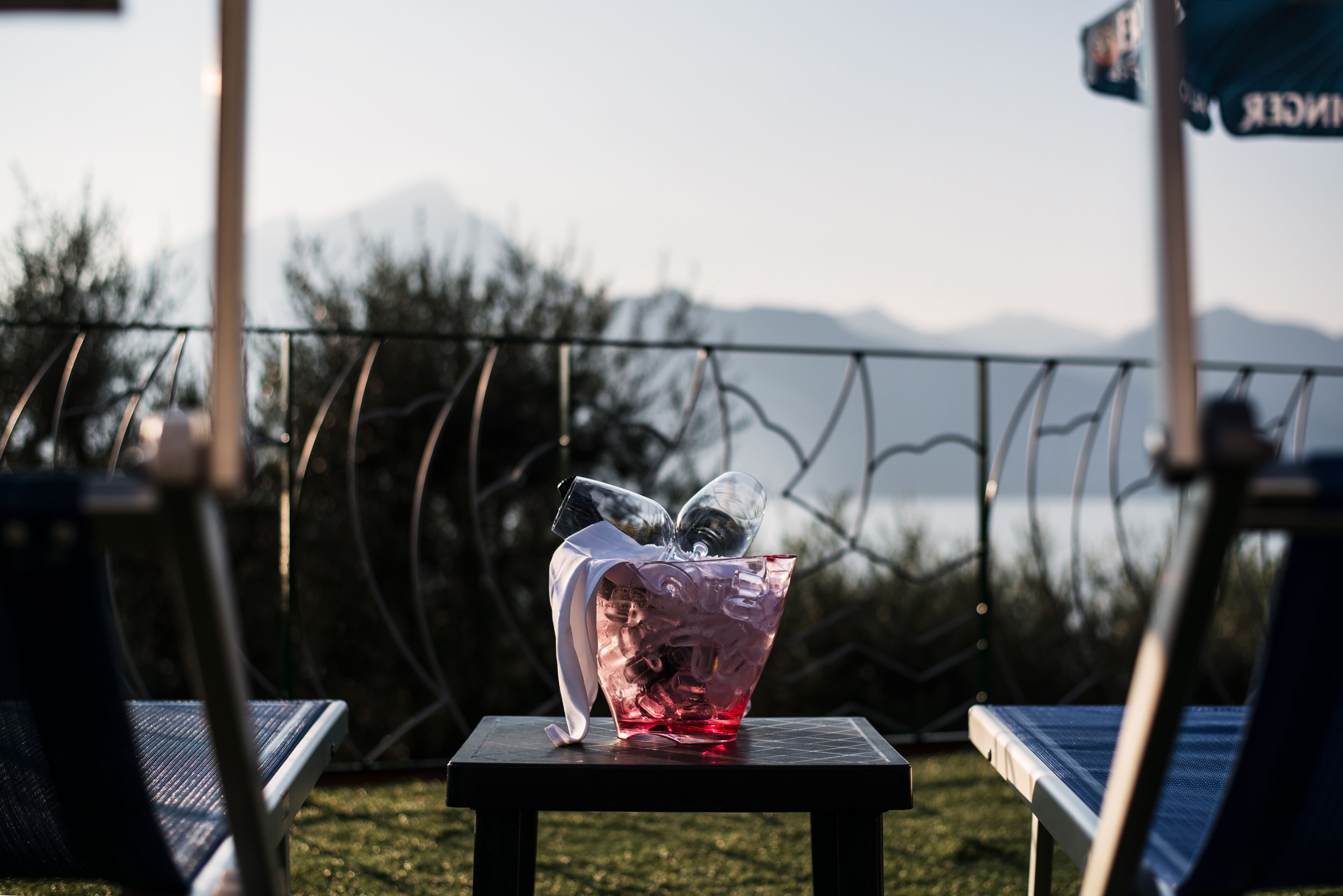 Un florero de vidrio con superficie reflectante sobre una mesa, con montañas y un cielo despejado de fondo.