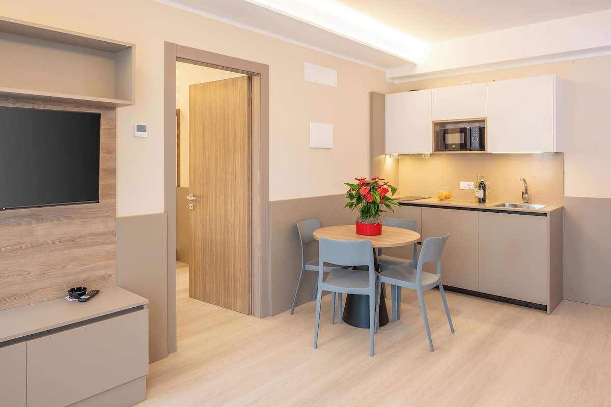 A modern kitchen with a microwave, sink, and a dining area with a table and chairs.