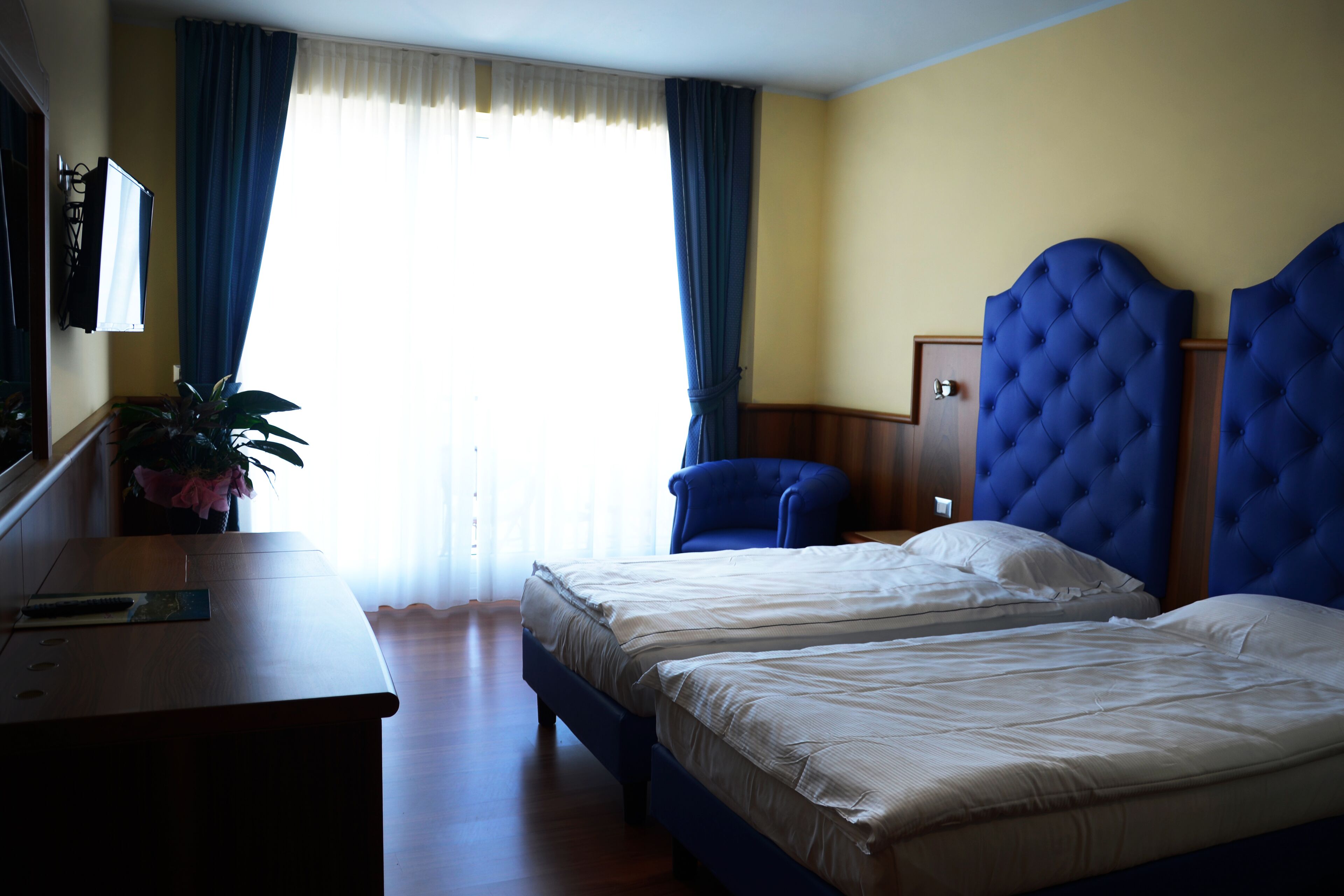 A hotel room with two beds, a desk, a chair, and a television.