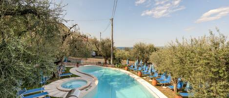 A swimming pool with blue lounge chairs and potted plants around it.
