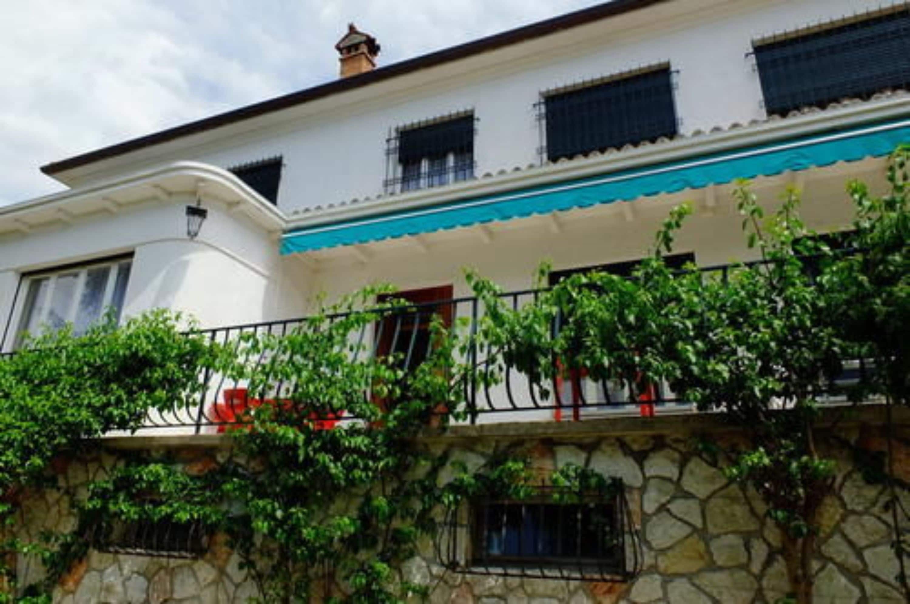 Un edificio blanco con toldo azul y muros de piedra.