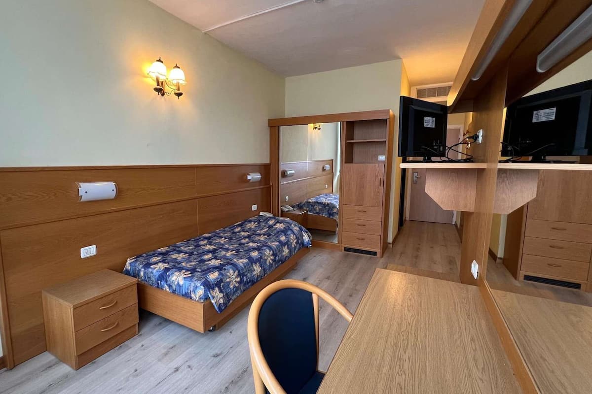 Una habitación pequeña con cama, escritorio, silla y armario.