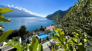 A pool area with clear blue water, surrounded by lush greenery and mountains in the background.