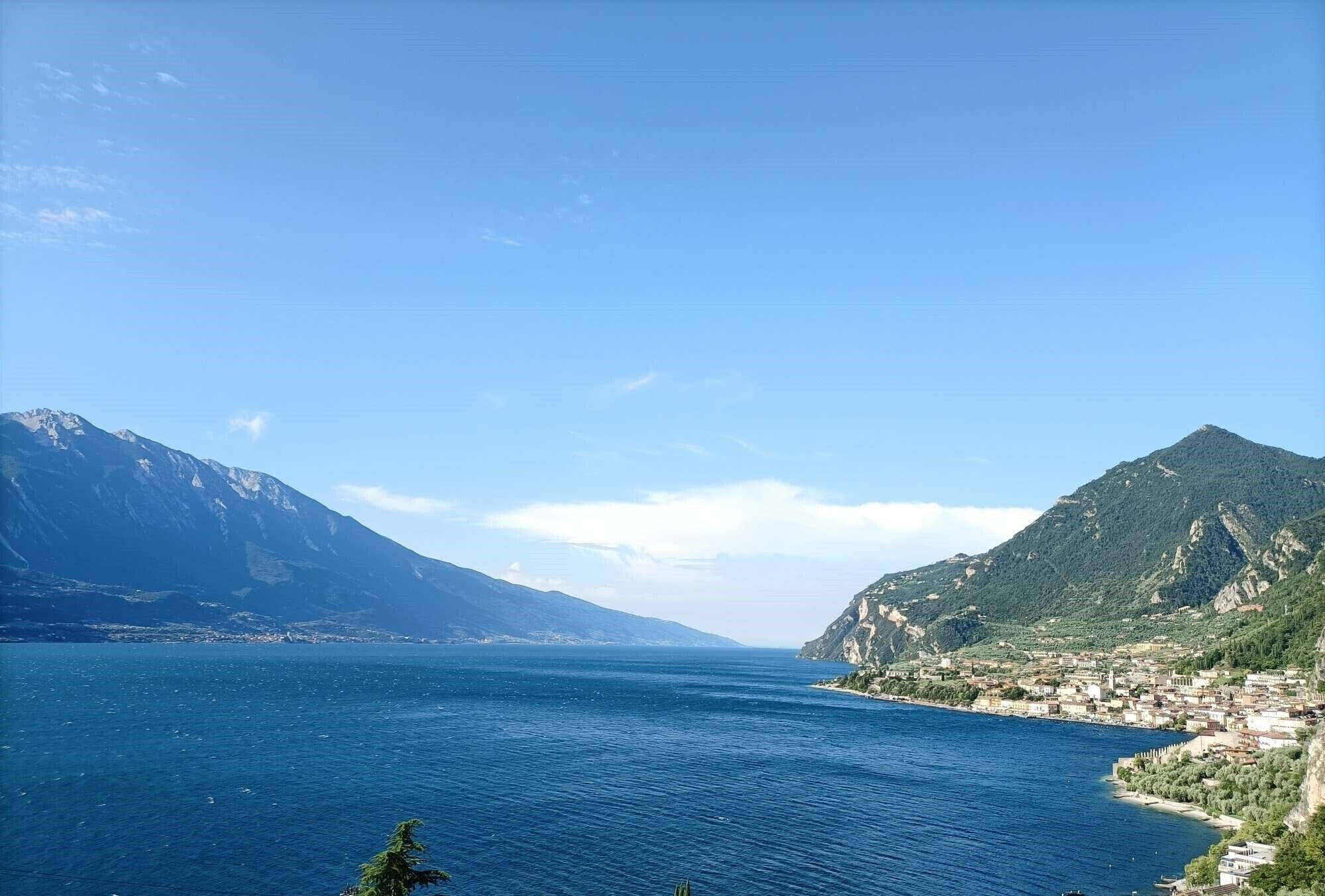 A coastal town with a large body of water, mountains, and a clear sky.