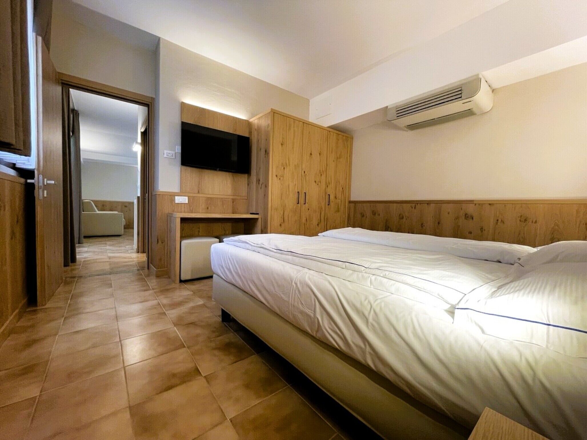 Ein Schlafzimmer mit einem Bett, einem an der Wand montierten Fernseher und einer Klimaanlage.