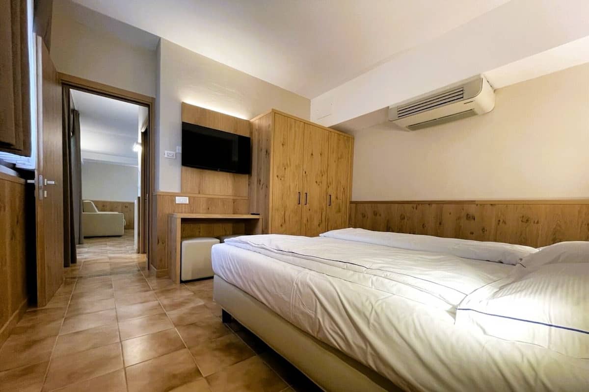 Un dormitorio con cama, televisor montado en la pared y aire acondicionado.