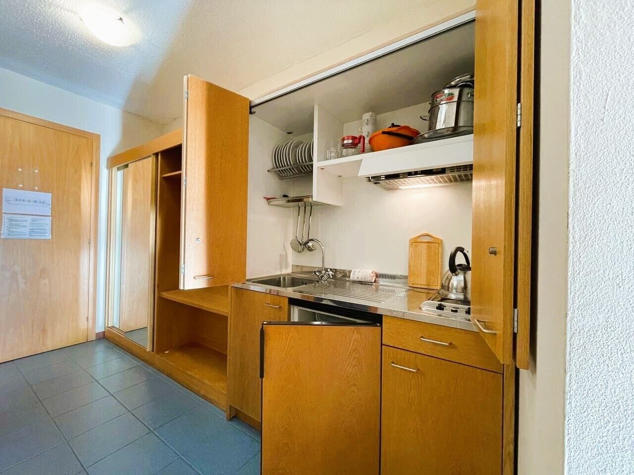 A compact kitchen with wooden cabinets, a built-in sink, and a stove.