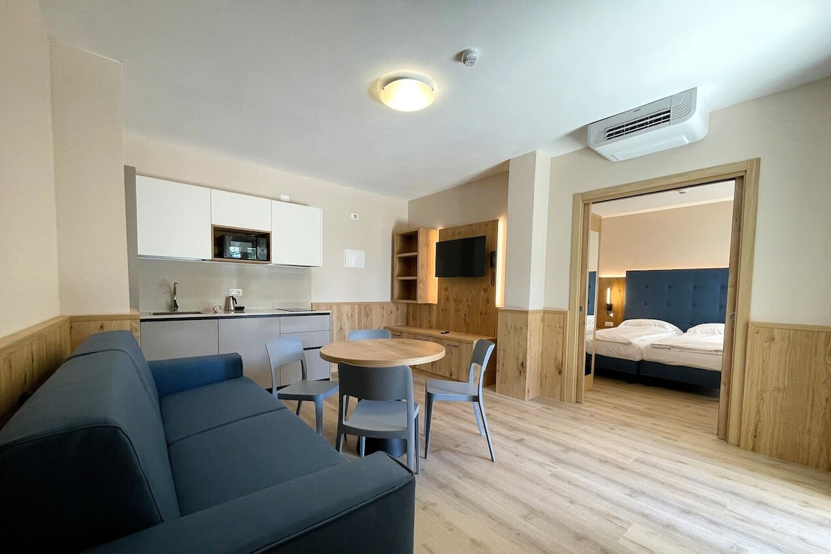 Una habitación pequeña con kitchenette, comedor y zona de dormitorio.