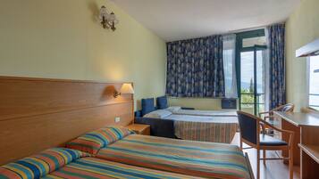 A hotel room with two beds, a desk, and a chair.