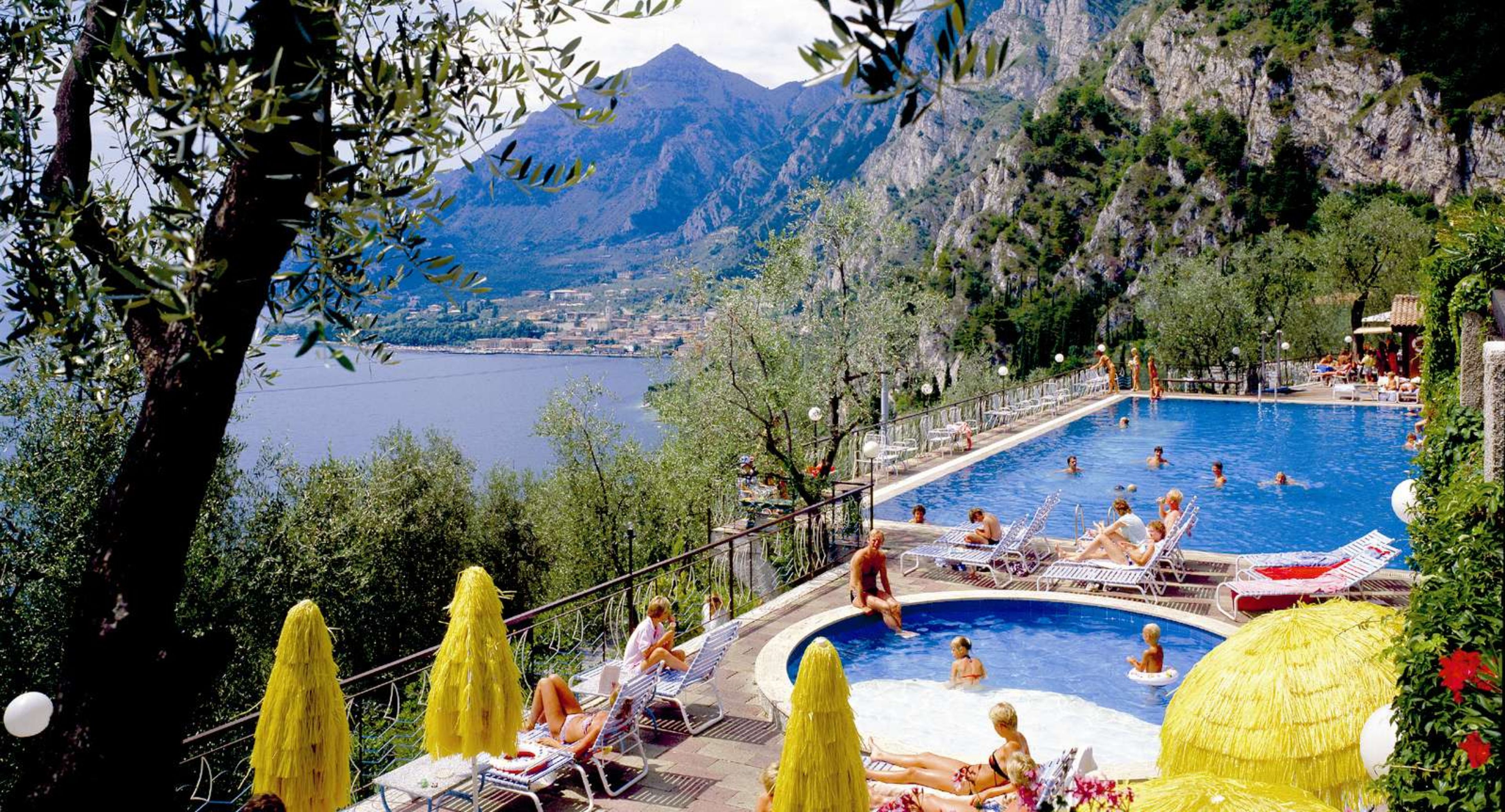 A pool area with a view of mountains and a lake.