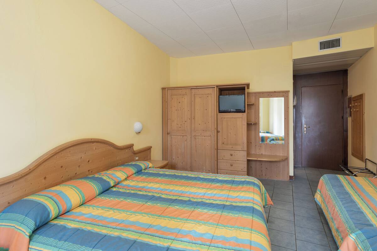 Ein Schlafzimmer mit zwei Betten, einem Holzschrank und einem Fernseher.