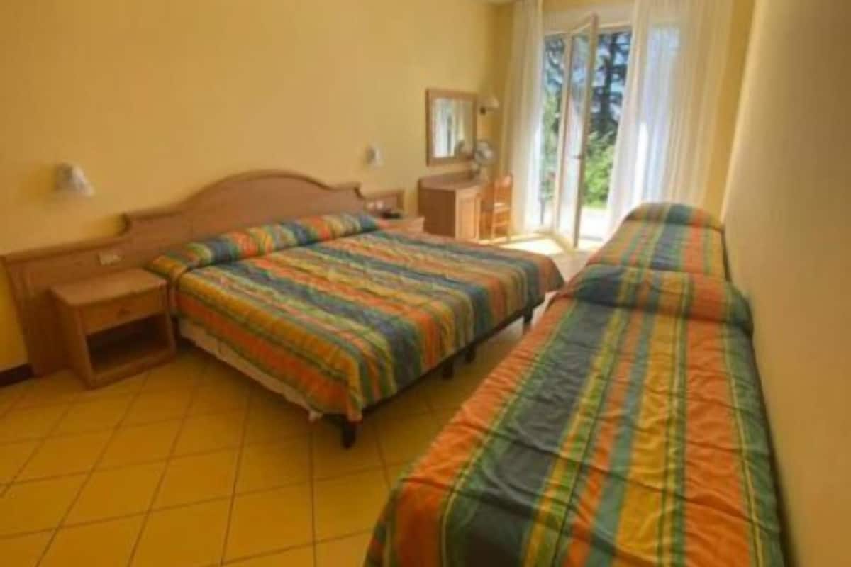 Ein Hotelzimmer mit zwei Betten, einem Schreibtisch und einem Fenster mit Vorhängen.