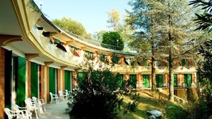 A courtyard with a curved building, outdoor seating, and greenery. - Hotel Marco Polo (Garda)