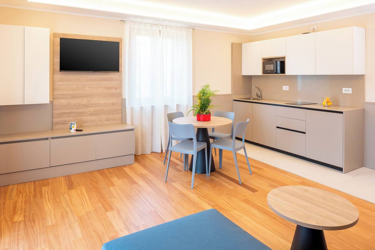 Une cuisine moderne équipée d’un four à micro-ondes, d’un évier et de placards. On y trouve également un coin repas avec une table, des chaises et une plante en pot.