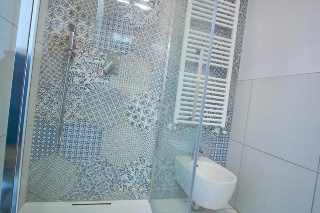 A bathroom with patterned tiles, a shower, a toilet, and a white sink.