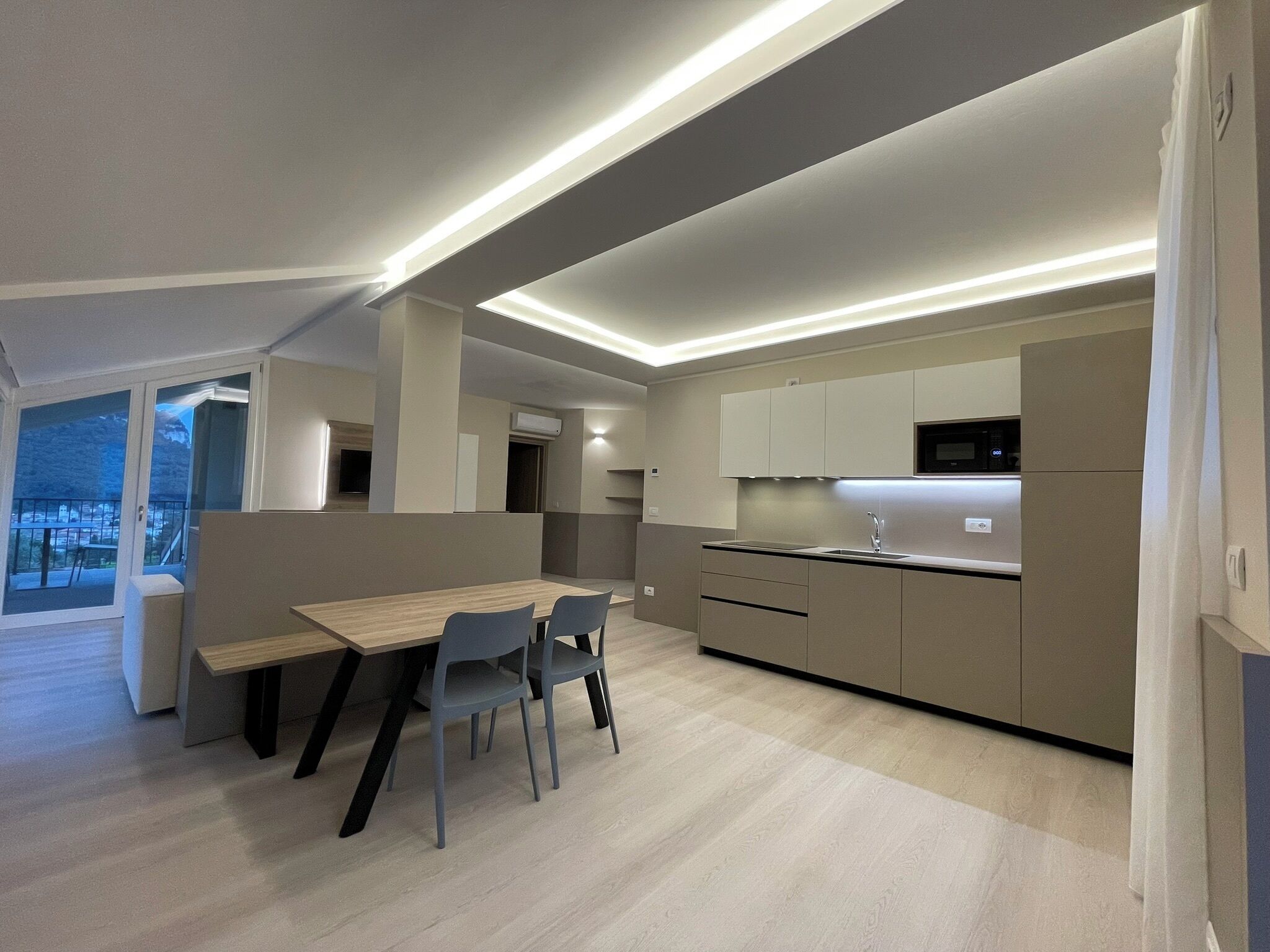 Een moderne keuken met een eethoek, inbouwapparatuur en uitzicht op de omgeving.