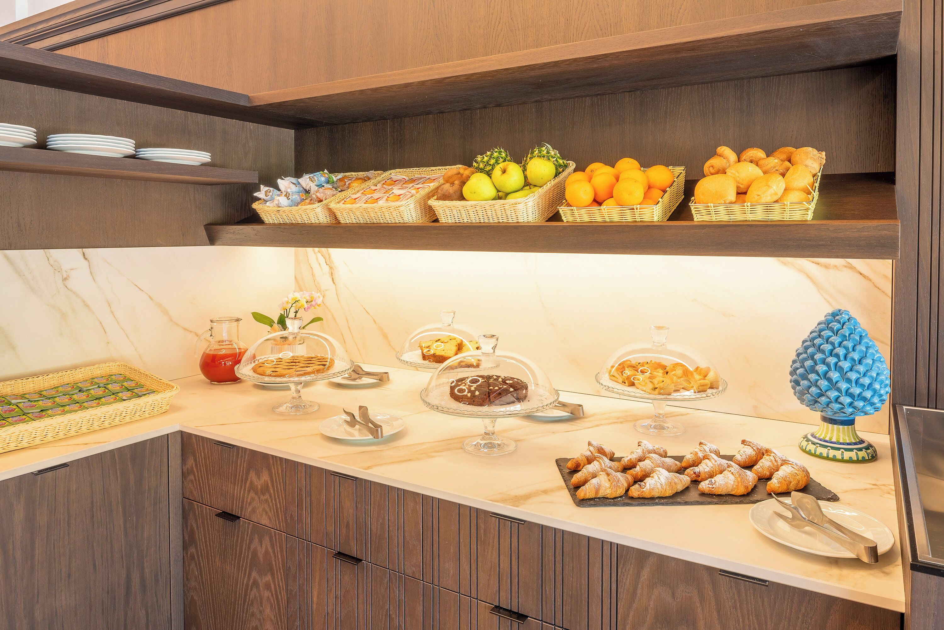 A buffet with various food items and a decorative blue vase.