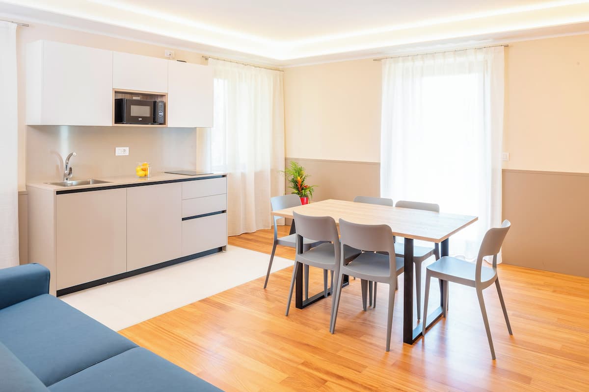 Une cuisine moderne équipée d’un four à micro-ondes, d’un évier et de placards. Un coin repas avec une table et des chaises est également disponible.