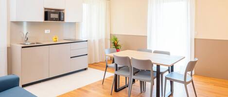 A modern kitchen with a microwave, sink, and cabinets. There is a dining area with a table and chairs.