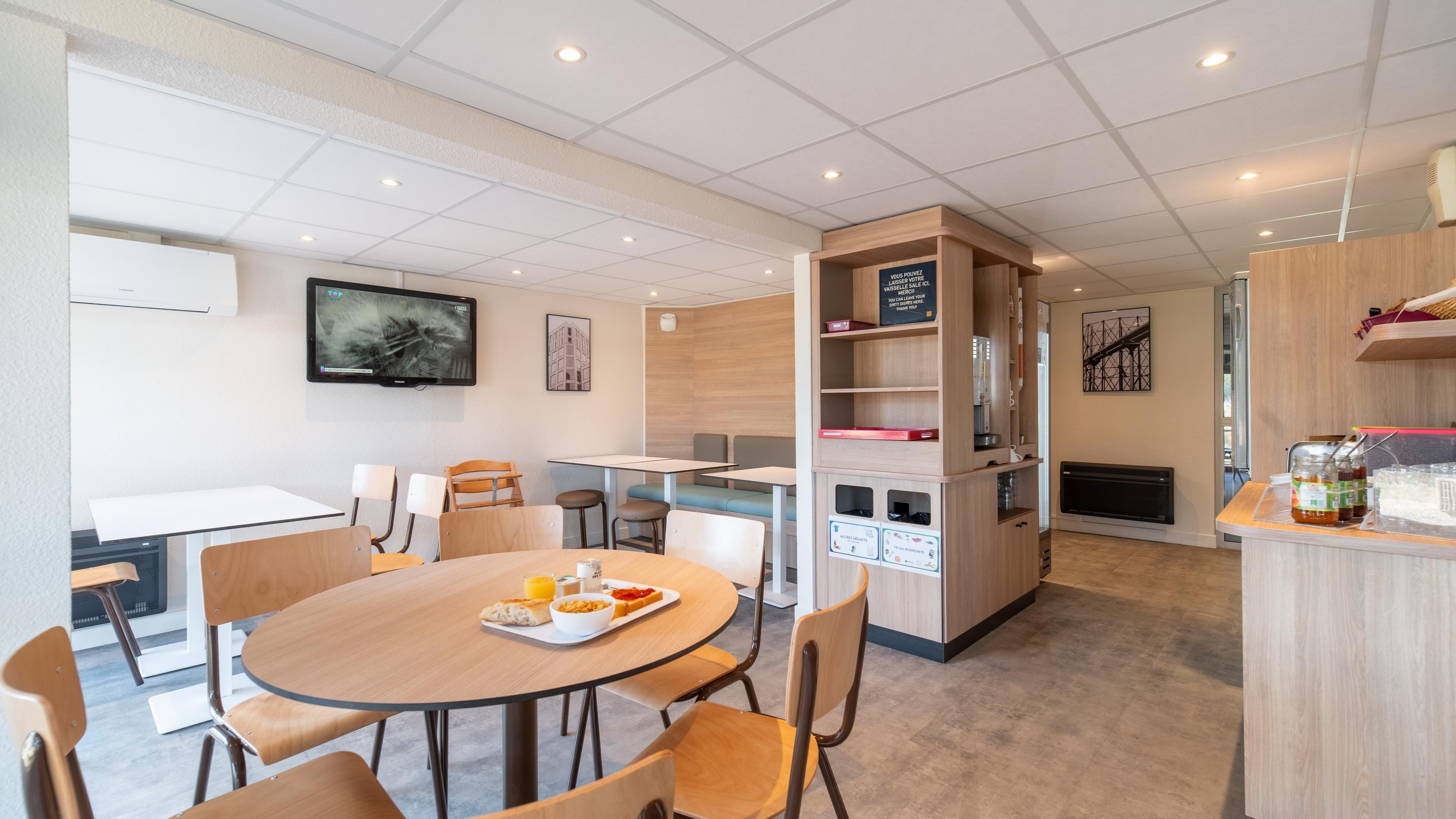 A modern dining area with round tables, chairs, and a central counter with a coffee machine.