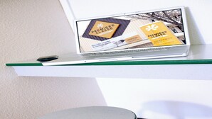 A laptop on a white shelf with a green edge, displaying a hotel brochure. - Premiere Classe Limoges Nord (Limoges)