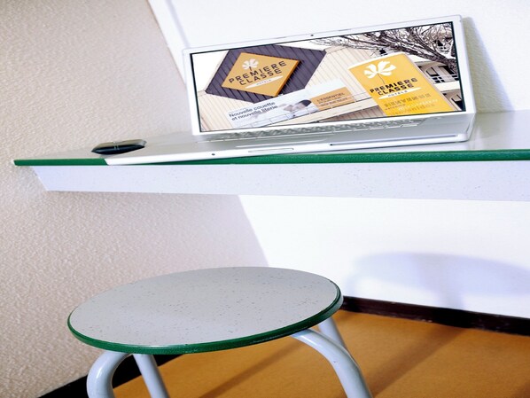 A laptop on a white shelf with a green edge, displaying a hotel brochure. - Premiere Classe Limoges Nord (Limoges)