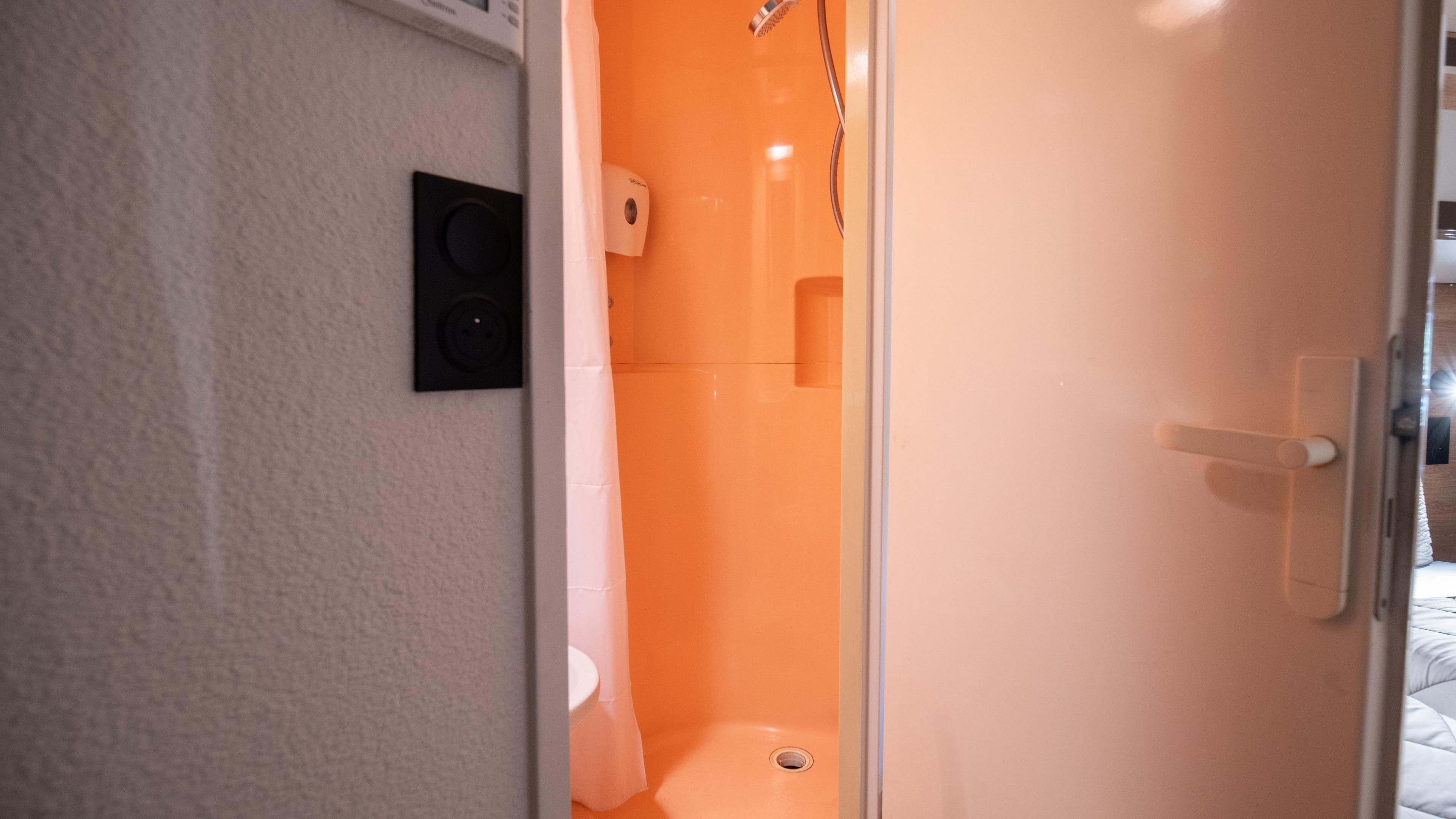 A bathroom with a shower, toilet, and a hand dryer.
