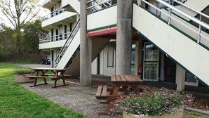 A building with a staircase, outdoor seating, and a fire extinguisher. - Premiere Classe Limoges Nord (Limoges)