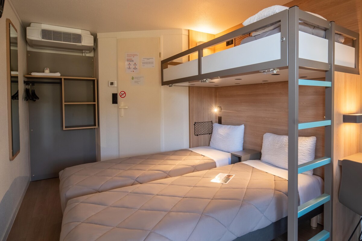 A bunk bed room with a desk and chair, a mirror, and a wardrobe.