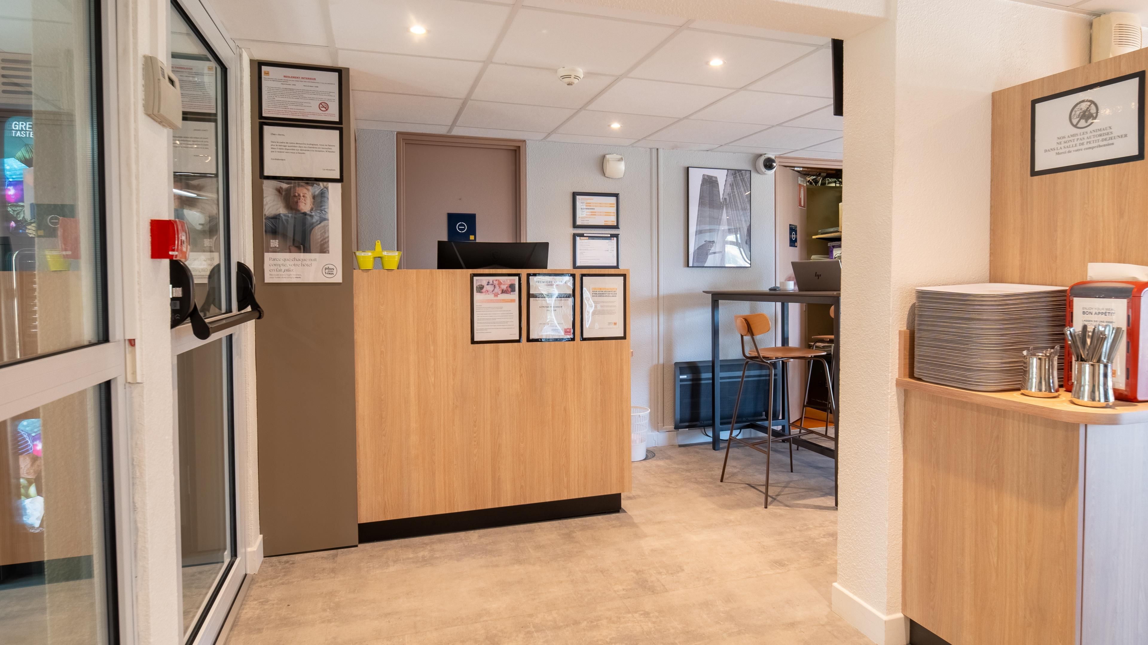 A reception area with a wooden desk, framed notices, and a computer.