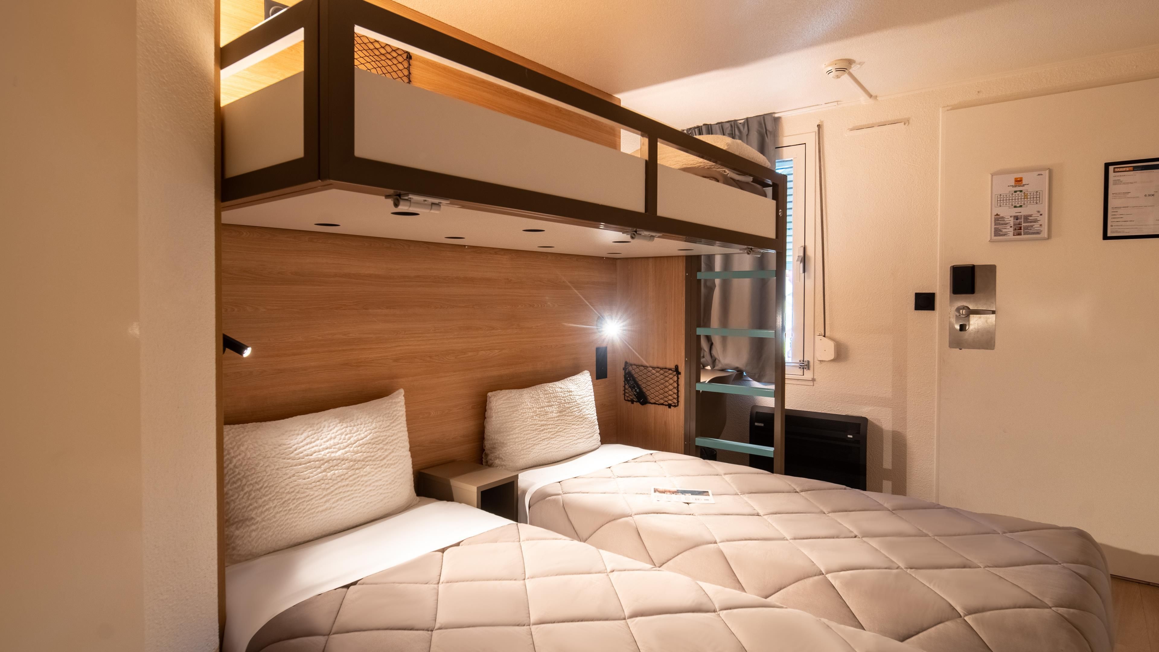 Una camera da letto con due letti, una testiera in legno e una piccola scrivania.