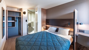 A modern hotel room with a large bed, a walk-in closet, and a bathroom visible through an open door. - Premiere Classe Limoges Nord (Limoges)