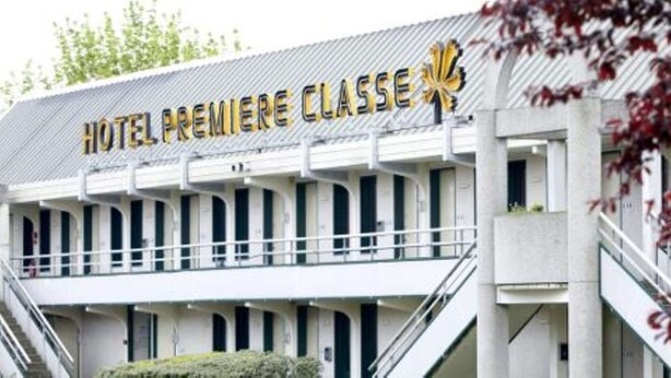 Un hotel con un cartel que dice "HOTEL PREMIERE CLASSE" y un emblema amarillo característico.