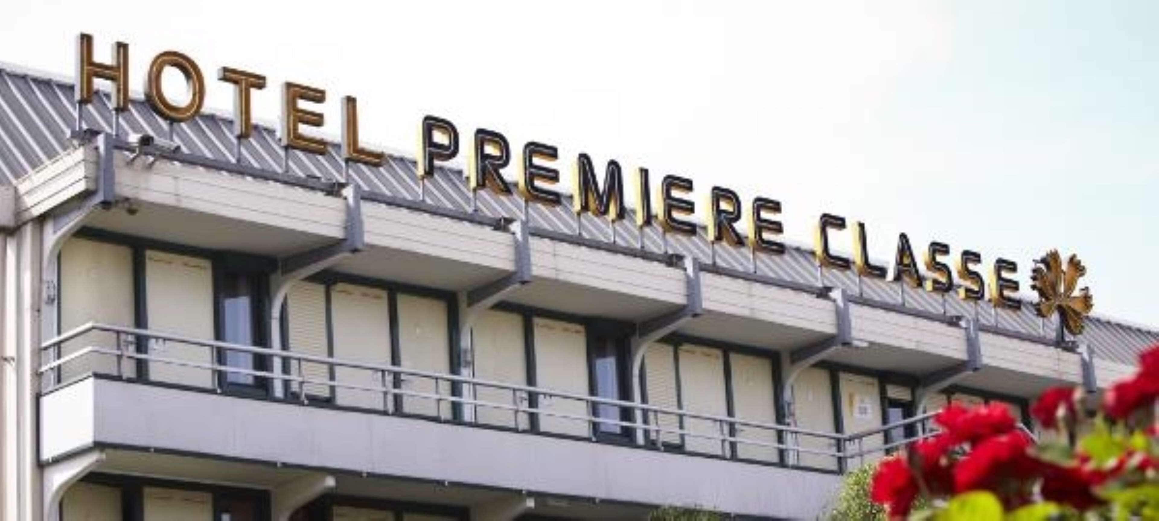 Un hotel con el letrero "HOTEL PREMIERE CLASSE" y balcones con barandillas.