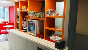 Una estación de café con una cafetera, un refrigerador y estantes llenos de productos de café.