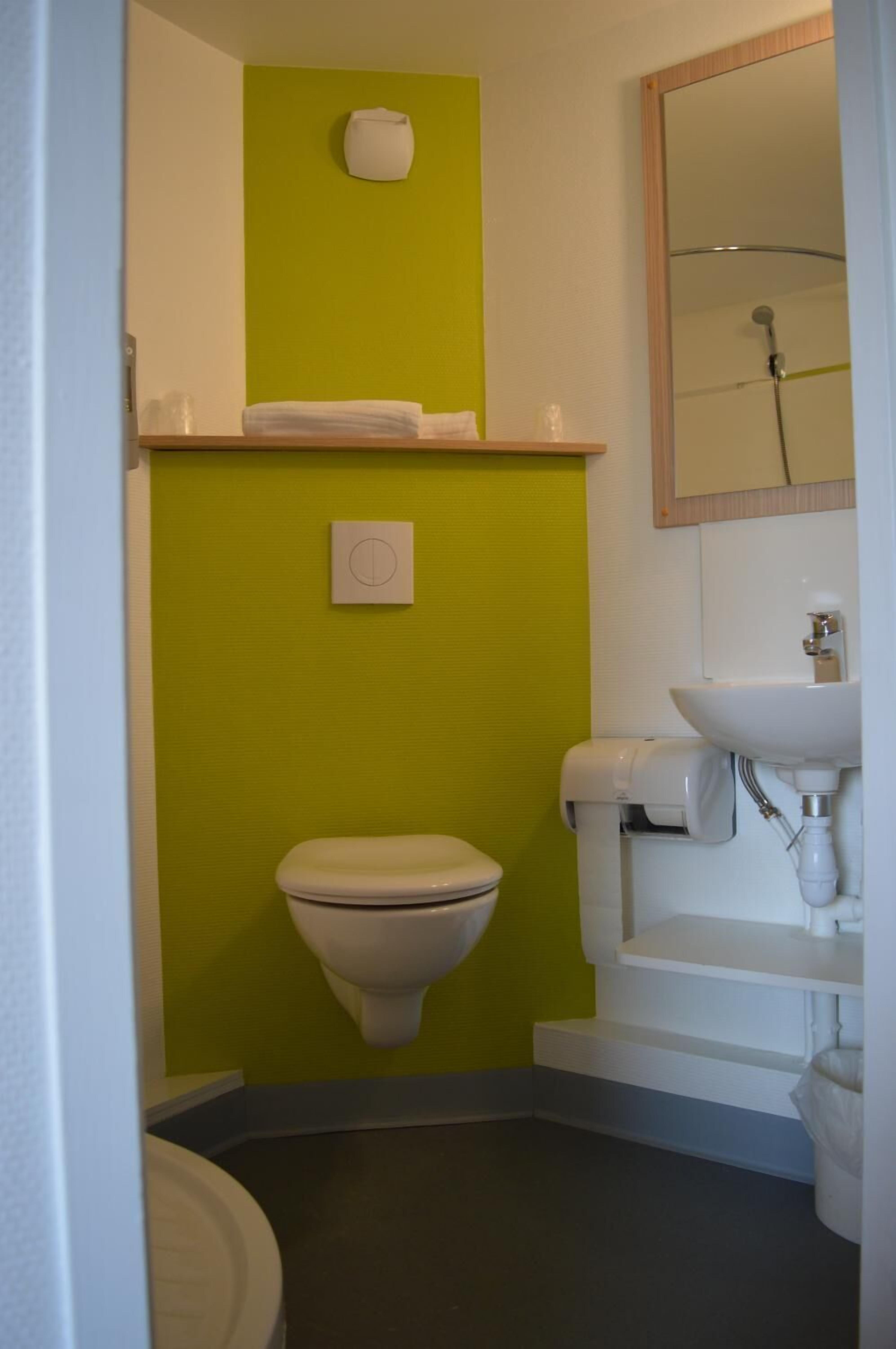 Un baño con inodoro, lavabo, espejo y toallero.