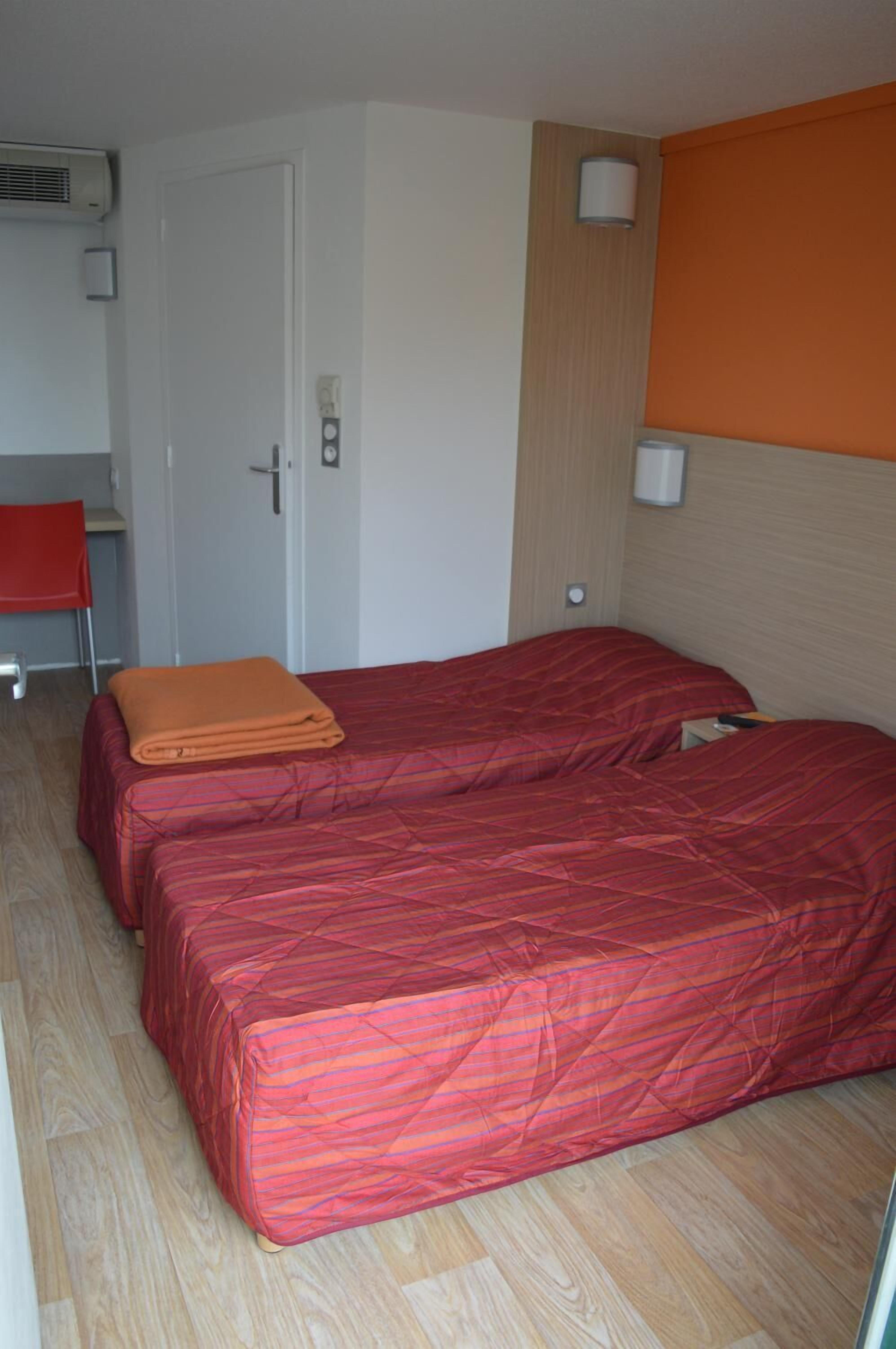 Une chambre avec deux lits, un bureau et une chaise.