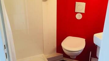 Une petite salle de bain comprenant des toilettes, un bidet et un porte-rouleau de papier toilette.
