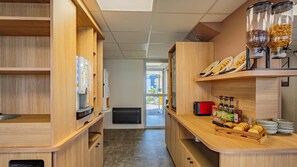 Una cucina moderna con mobili in legno, una macchina da caffè, un tostapane e un espositore per il pane.
